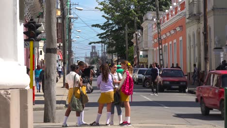 school children congregate on a busy corner in the  cuban town of cienfuegos