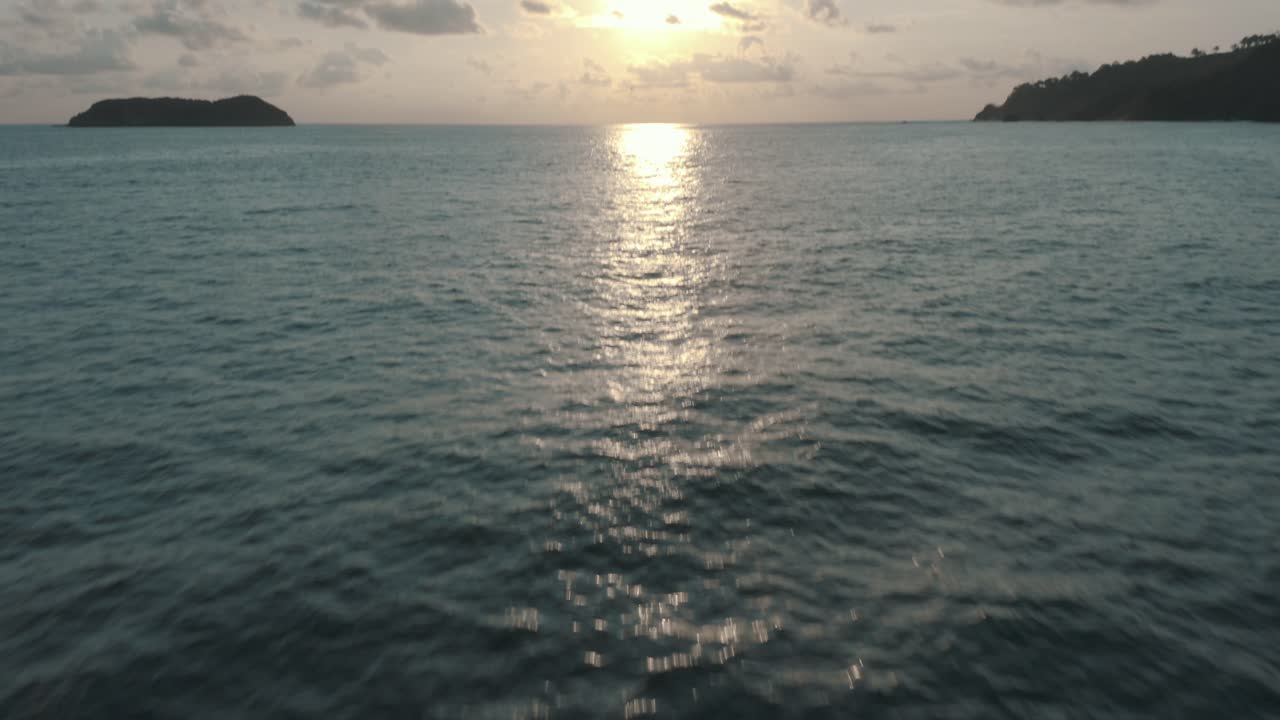 antena cinematográfica de drones volando sobre el agua revelando la puesta de sol en costa rica durante el verano