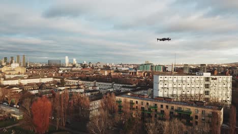 Aerial-drone-view-of-another-flying-black-drone-in-the-skies-of-London-during-afternoon-in-a-cloudy-weather