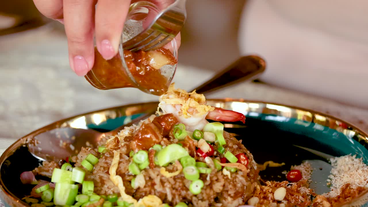 vertiendo salsa sobre pasta de camarón y arroz frito