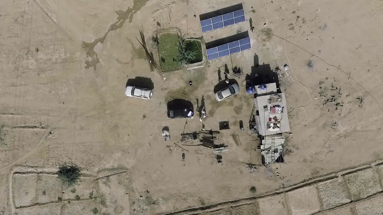 Una veduta aerea rotante dall'alto su auto, pannelli solari fotovoltaici e una capanna.