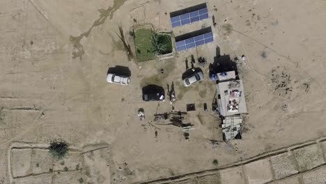 A-top-aerial-rotational-view-over-the-cars,-solar-electrical-panels-and-a-hut