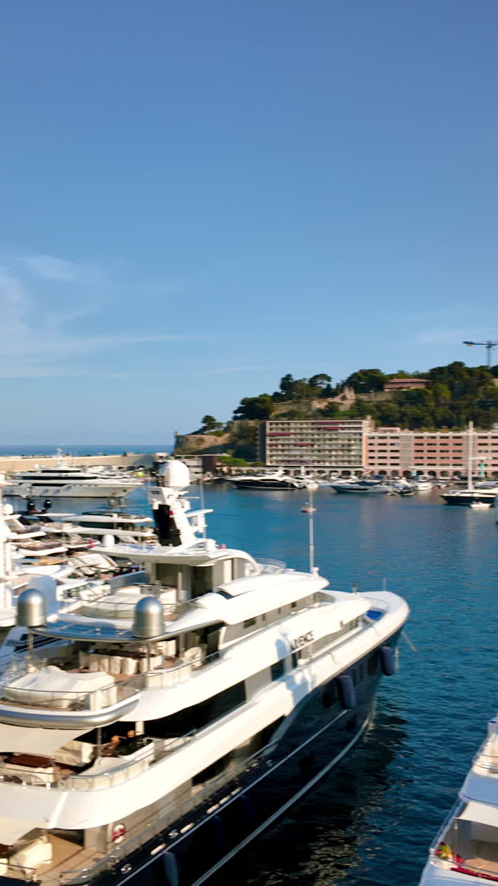 Vista di barche bianche ormeggiate nel porto turistico di Monaco, con lo skyline della città sullo sfondo. Verticale