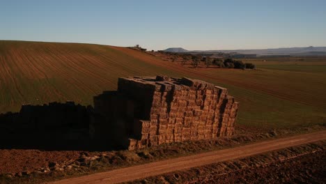 Aerial-shot-of-straw-bales-stacked-in-a-big-block-on-a-plowed-field