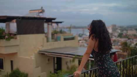 a young, attractive woman is happy to watch the sunset over the ocean from her rooftop