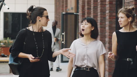 multiethnic businesswomen walking on street and speaking