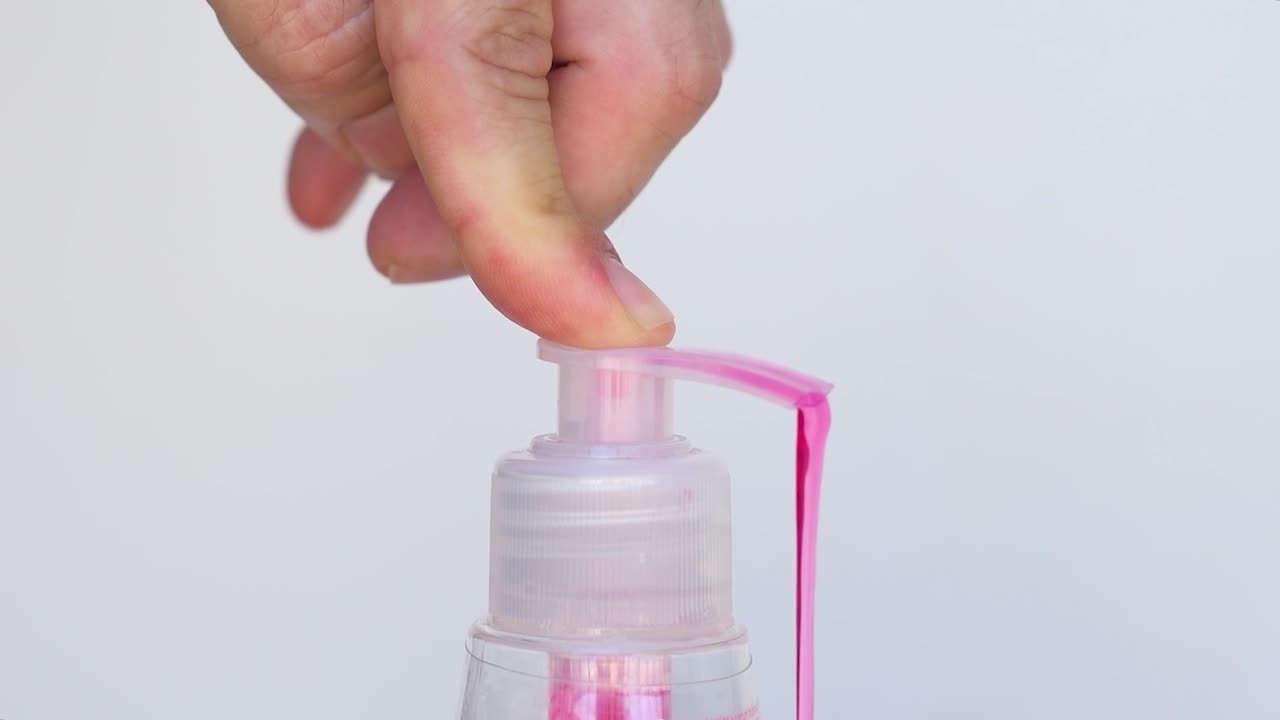 presionando la botella de jabón de manos líquido rojo
