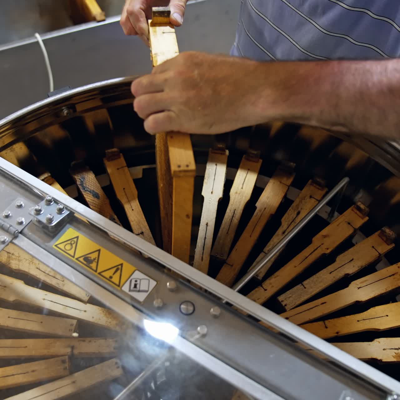 Honey harvesting. Apiarist putting frame with honeycomb into a centrifuge device. Honey extractor with many frames full of honey. Production of healthy product