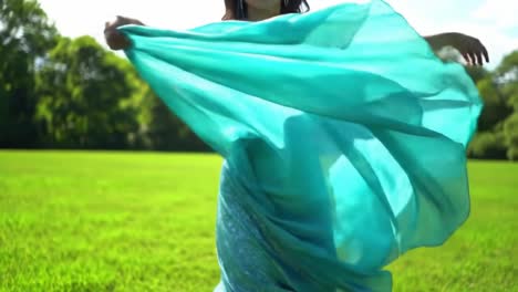 a graceful woman twirls in a flowing turquoise dress, embodying elegance and movement against a lush green backdrop, capturing the essence of freedom and beauty in nature