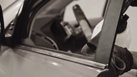 ingeniero profesional con guantes negros usando hábilmente una pistola de tornado para limpiar la ventana del coche