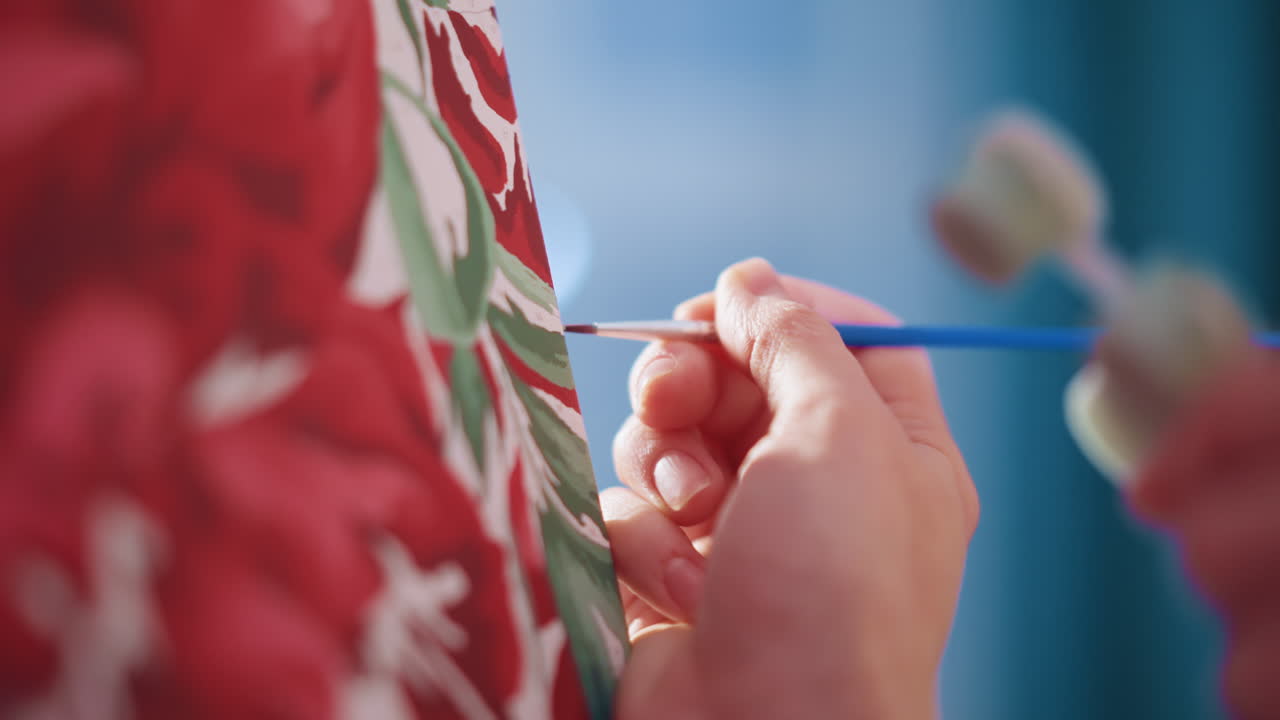 Closeup White Hands Painting Leaf Detail On Floral Canvas, Cool Daylight, Tiny Brush Strokes, Careful Layering Of Greens, Roller Tool In Background, Patient Technique, Intimate Craft Moment