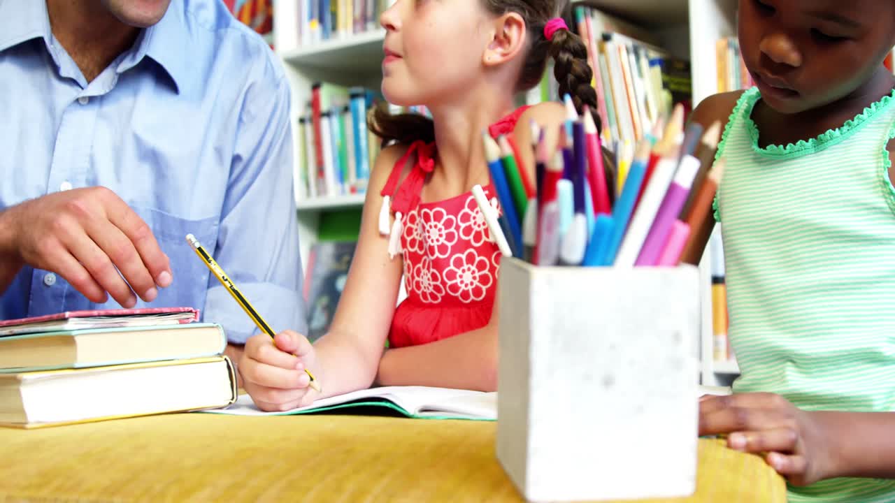 maestro ayudando a los escolares con su tarea en la biblioteca de la escuela