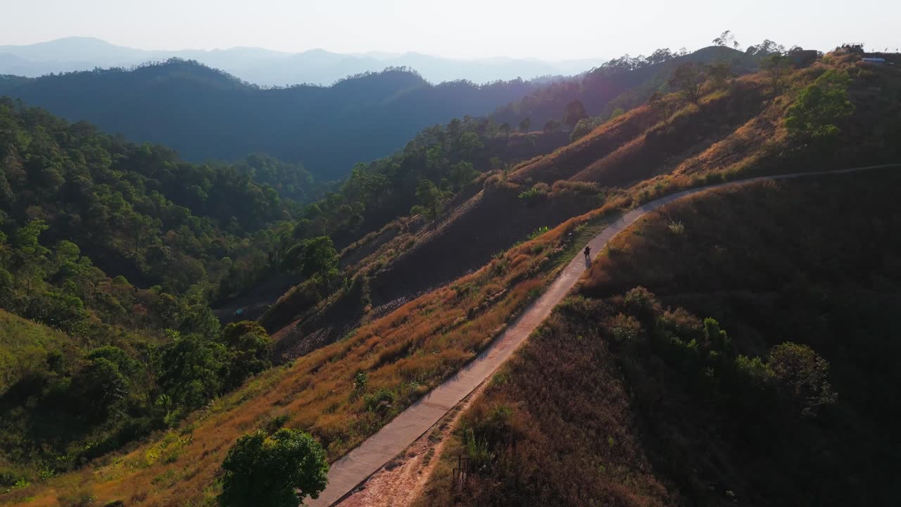 Motorcycle riding at sunset on mountains scenic single track trail ridge reaching camping spot