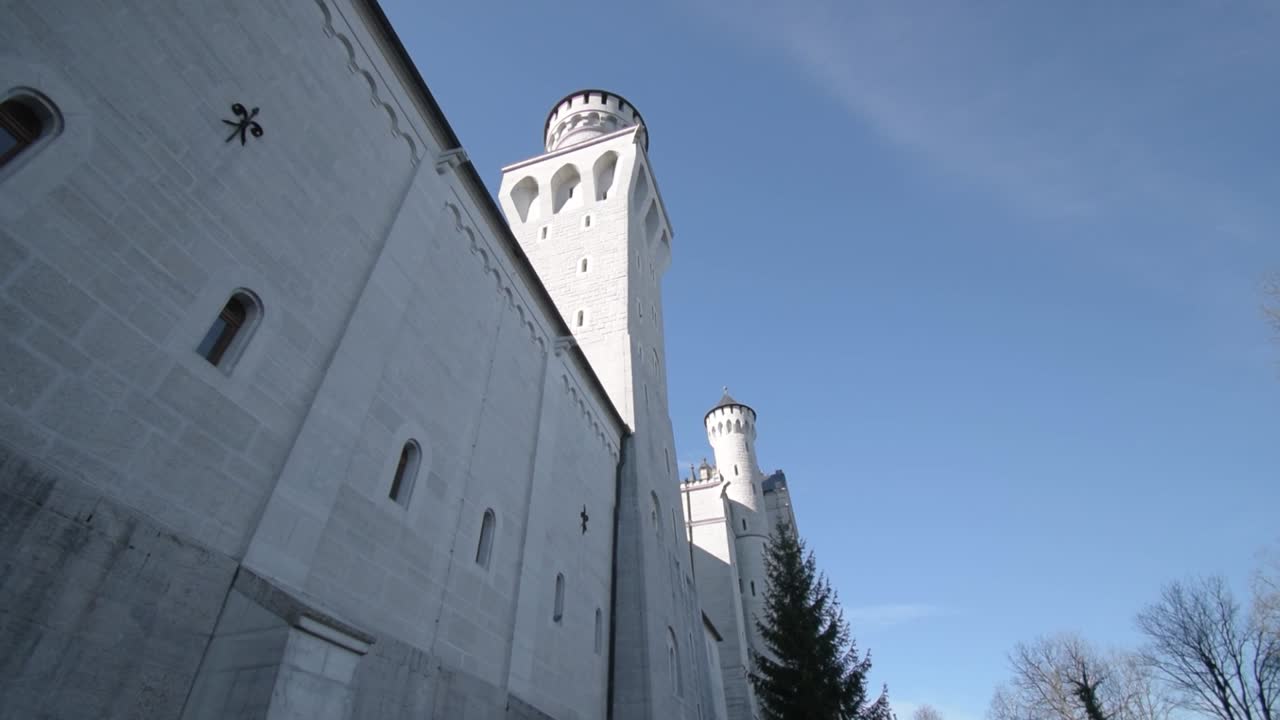 Facciata esterna del Castello di Neuschwanstein sotto un cielo blu.