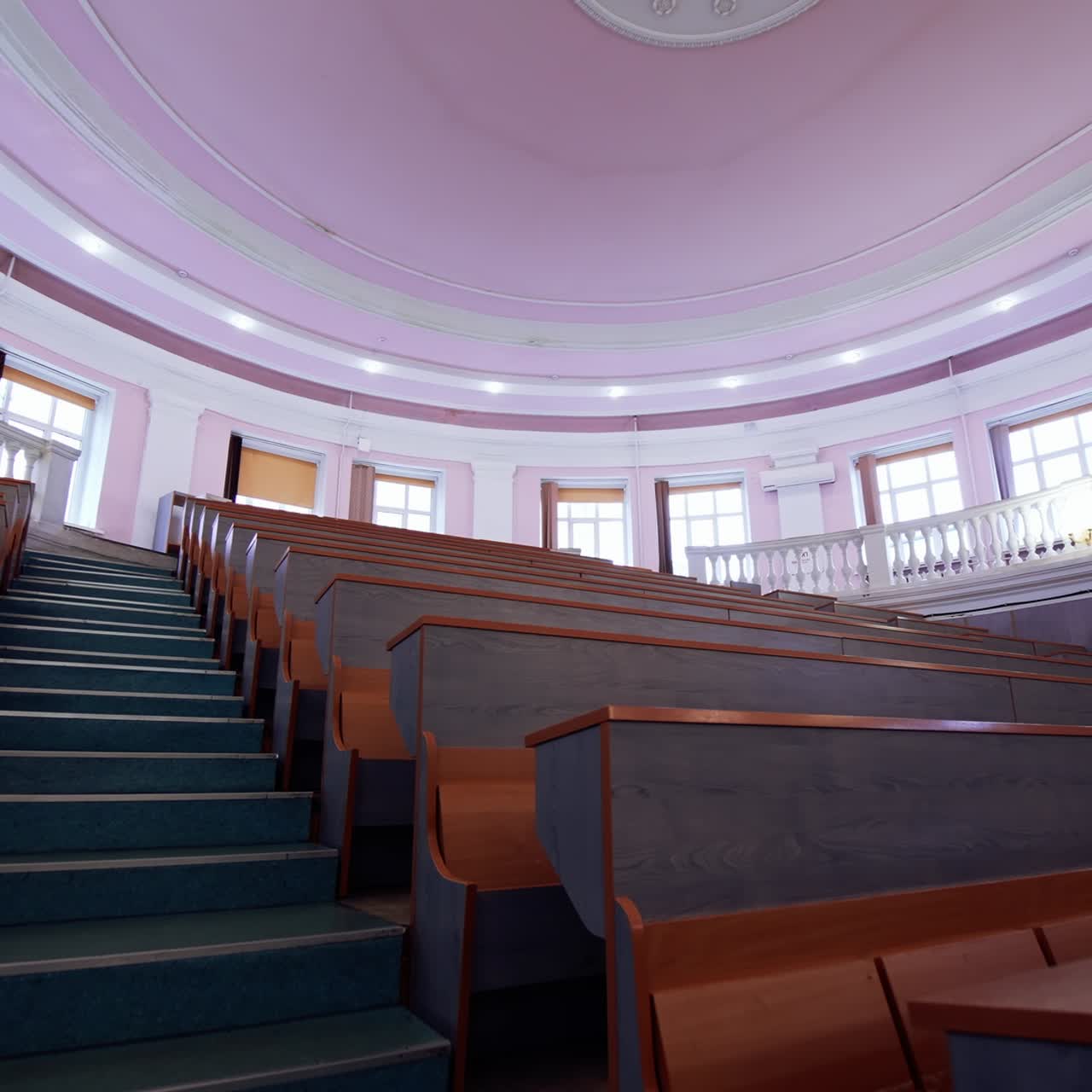Educational hall with nobody. Empty auditorium with wooden desks. Modern large meeting room with rows of tables and stairs