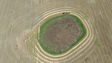 vista de pájaro de una empacadora de heno empacando heno en el campo en saskatchewan, canadá en un día soleado - antena