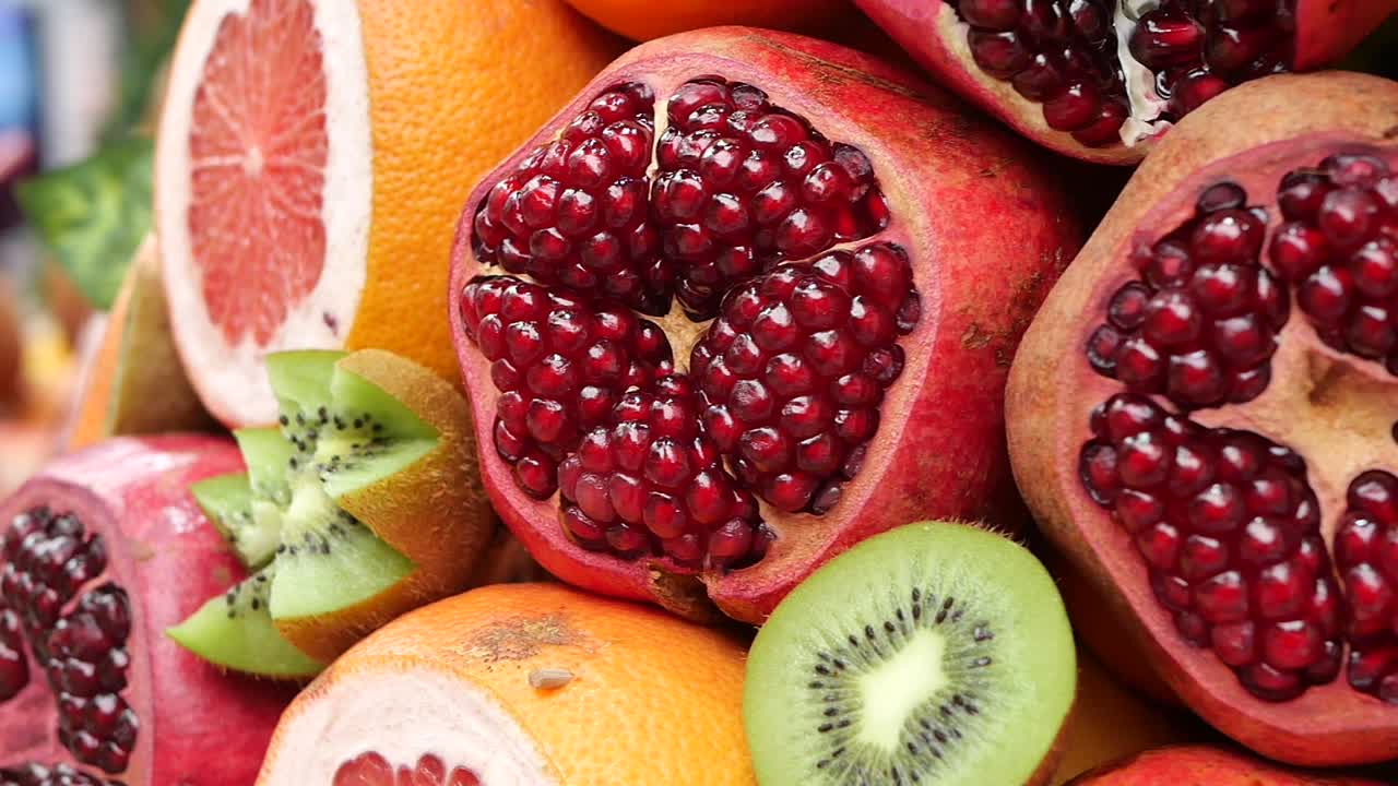 Nærbilde av nyskårede granatepler, kiwi og sitrusfrukter