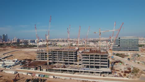 an office building under construction with many cranes on it - pullback rotation shot