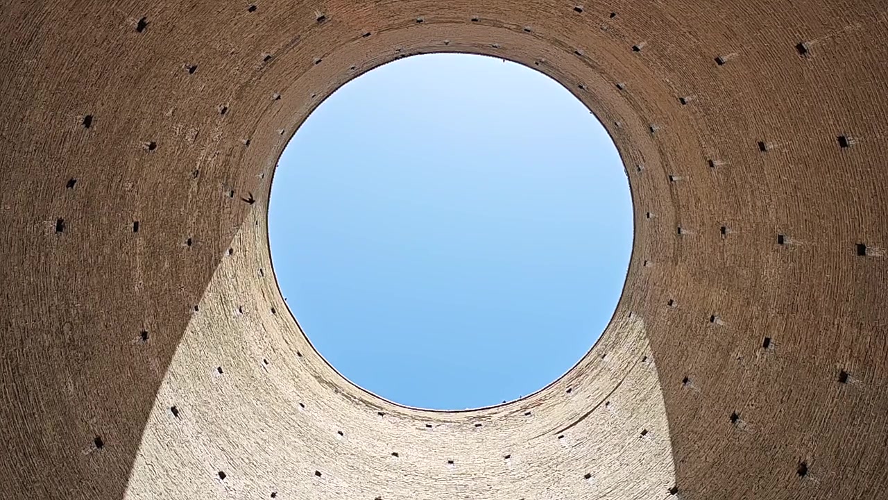 高いレンガの塔の中で空を見上げながら飛ぶ鳥