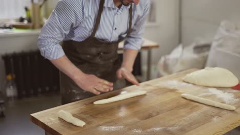 el panadero guapo amasa la masa y hace el pan. el chef prepara la masa con harina. enrollando la masa en la mesa. las manos del panadero se cierran. preparando el pan. las manos masculinas se cierran