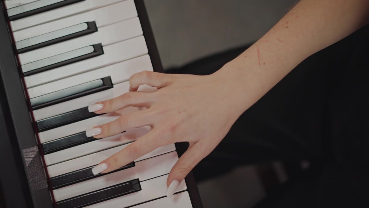 Mani femminili che praticano la diteggiatura al pianoforte, ripresa dall'alto in studio con tastiera digitale, energia concentrata del coach, tecnica precisa e lavoro sul tempo, prova per performance o registrazione, unghie curate.