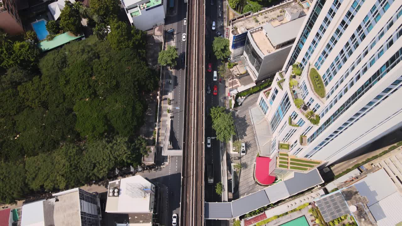 Ripresa aerea cinematografica 4K con movimento in tilt-up sopra la ferrovia BTS tra i grattacieli della città di Bangkok.
