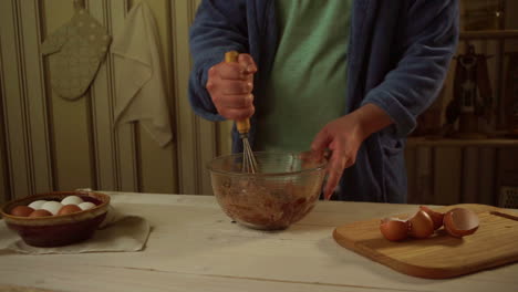 man whisking baking ingredients into glass bowl at kitchen. homemade cake