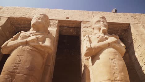 tall statues of pharoes in the karnak temple, luxor egypt. carved details on the pillars and walls.
slow movement towards the statues with a pan up.