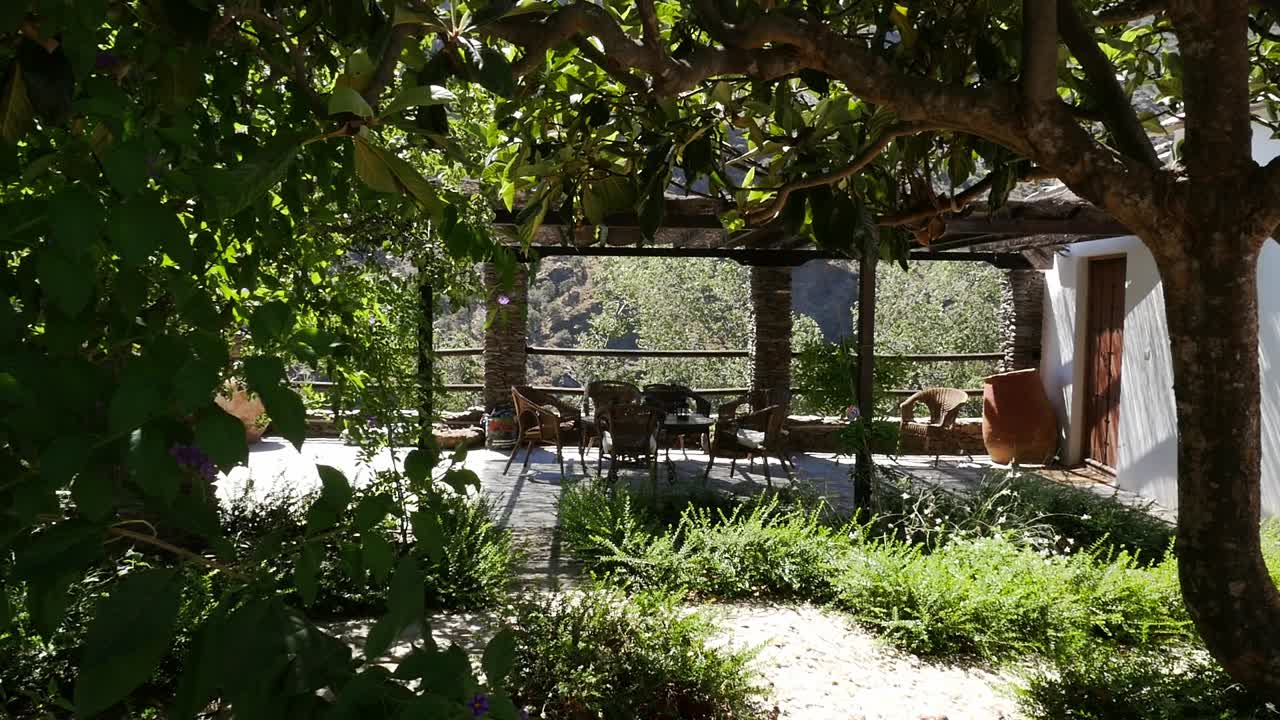 Outdoor terrace with pergola covered in vegetation and garden furniture, in the Alpujarra of Granada