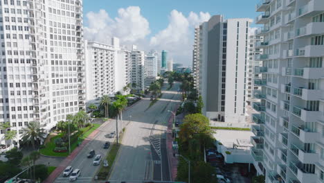 Aerial-view-of-wide-multilane-road-leading--between-rows-of-high-apartment-buildings-in-luxurious-residential-urban-borough.-Miami,-USA