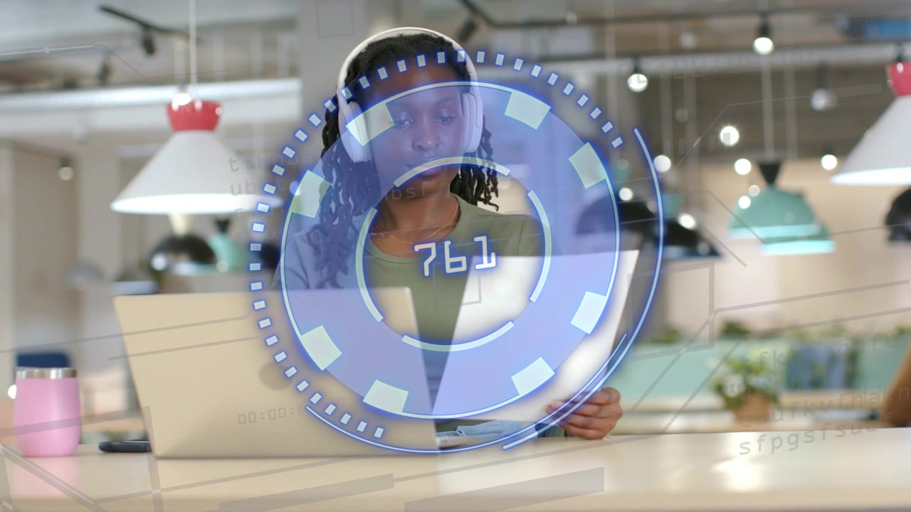 Woman working at desk reading paper at laptop while AR UI appearing, rotating, verifying tech data