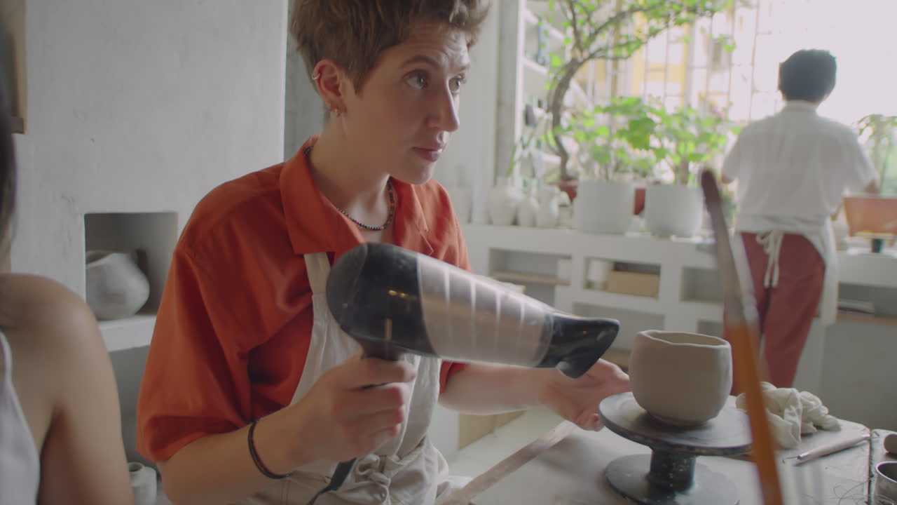 Woman Drying Ceramic Mug with Hairdryer at Pottery Class