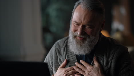 Cheerful-old-man-having-video-call-home.-Happy-gentleman-using-computer-indoors.