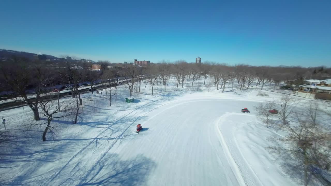 몬트리올의 파크 라 폰테인 (parc la fontaine) 에서 눈 인 경로를 가로질러 부드럽게 이동하는 fpv 드론, 눈 청소 차량이 효율적으로 작동합니다.
