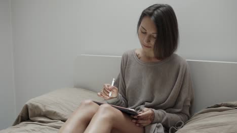 woman drawing on tablet in bed