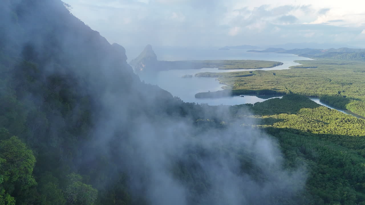 Clouds sweep across lush forested mountains of Phuket, aerial drone backdrop background