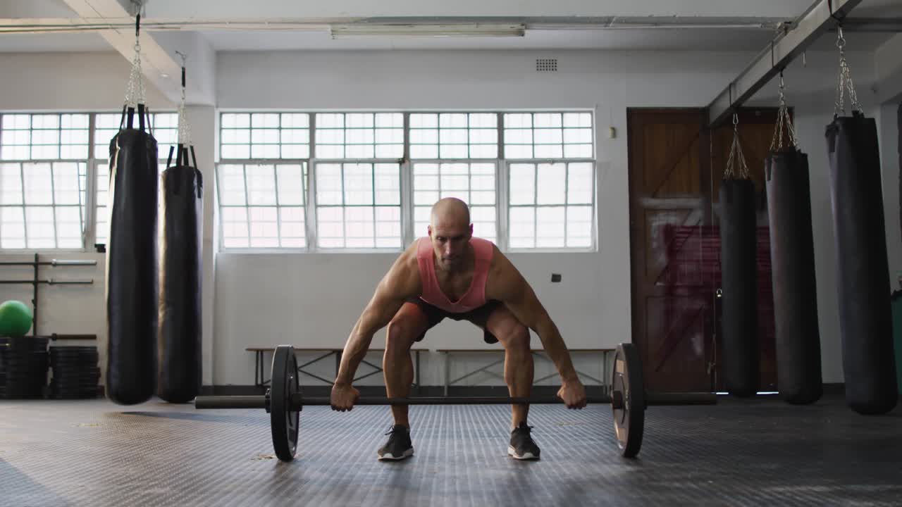 Sollevatore di pesi di sesso maschile che spinge con le gambe, iniziando un sollevamento in palestra, generando icone social intorno a lui che promuovono il fitness