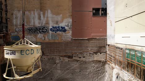 concrete bucket suspended over a deep urban construction excavation