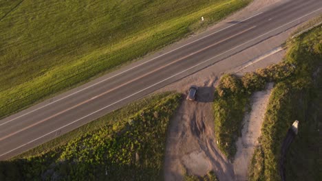 vista aérea superior de un automóvil negro que conduce desde la carretera rural hasta la ruta principal en el entorno natural en mar de las pampas, argentina