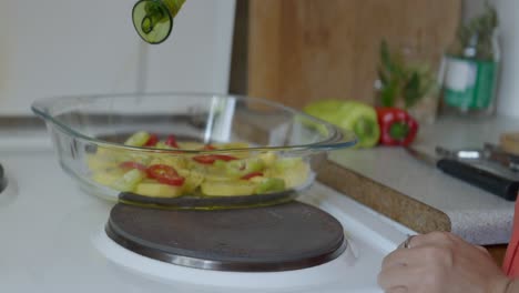 Close-up-shot-of-a-woman-pouring-olive-oil-in-a-baking-tray,-in-a-small-kitchen-with-natural-light