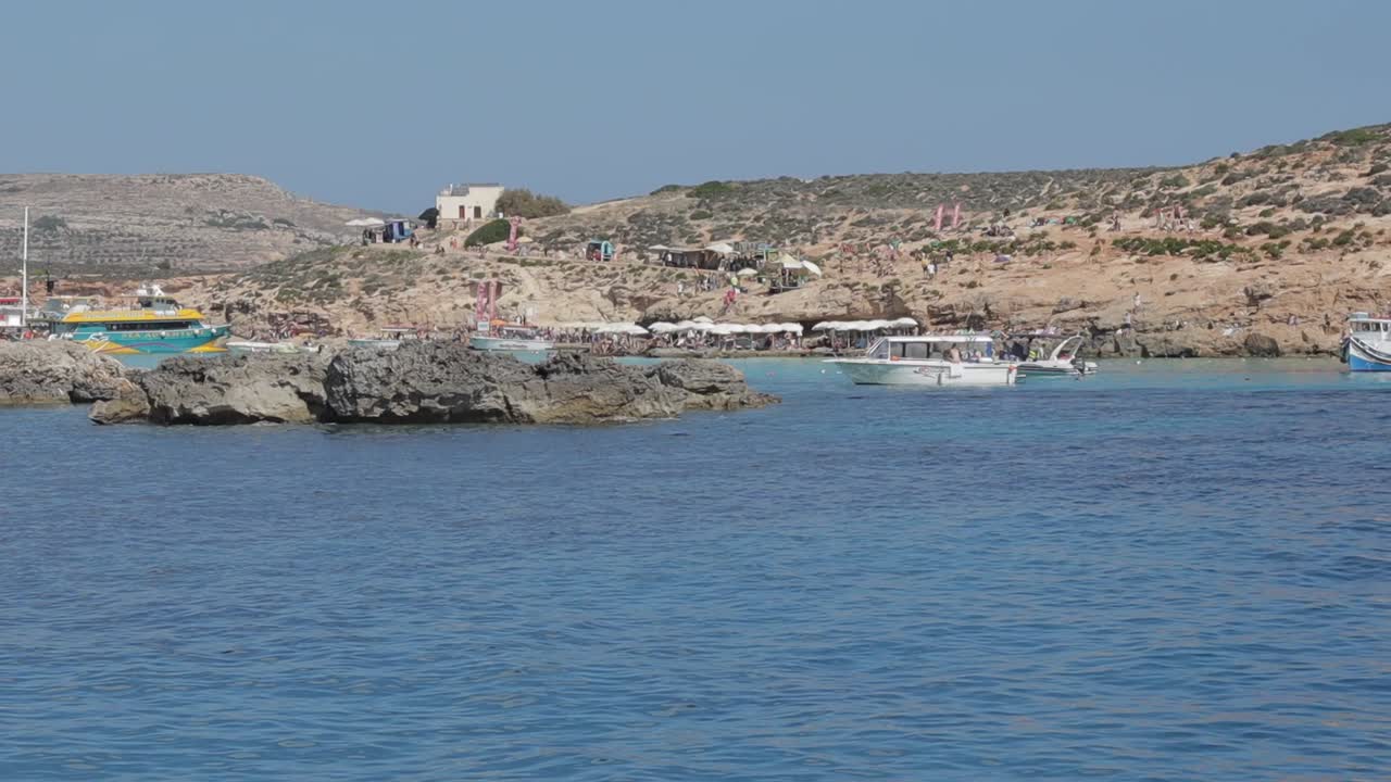 una escena pintoresca que captura la costa de malta, con tablas atracadas cerca de la costa y islas adornadas con vegetación baja en un día soleado, ilustrando el concepto de belleza natural y tranquilidad