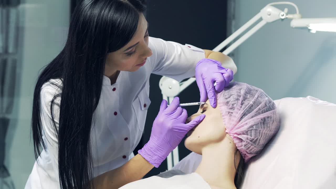 Beautiful woman with closed eyes gets beauty facial injections by beautician in clinic. Eye zone. Aesthetic Cosmetology