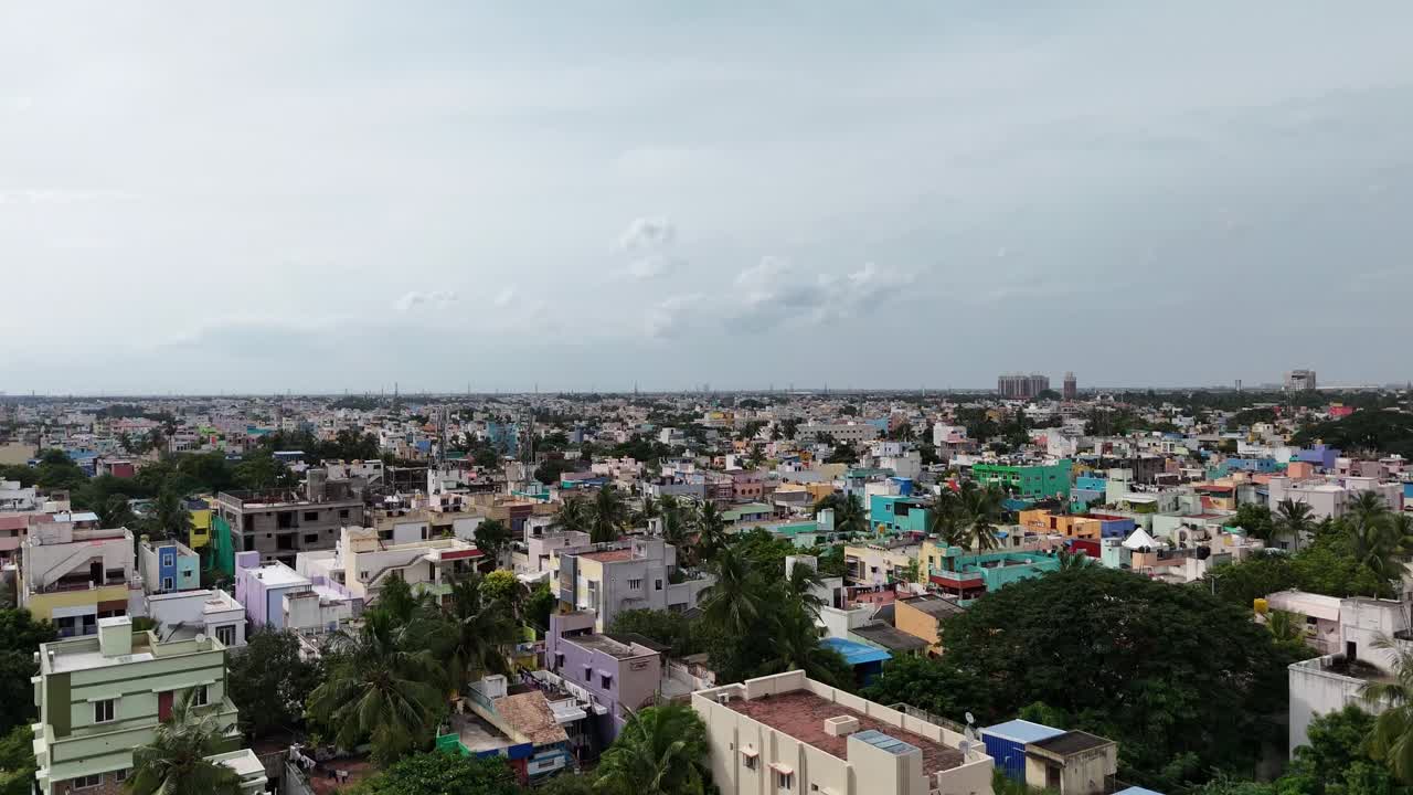 A wide, high-angle aerial view of a densely packed urban landscape, typical of a major Indian city Chennai with a of low to mid-rise residential and commercial buildings painted in a variety of colors