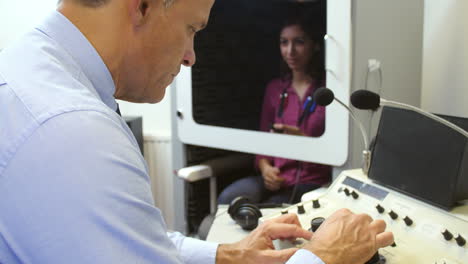 audiologist carrying out hearing test on female patient