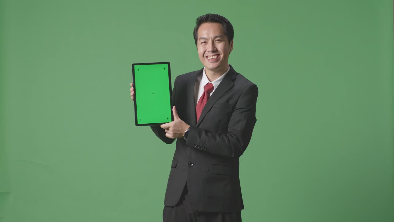 스튜디오에서 녹색 스크린 배경에 태블릿 녹색 화면을 보여주는 아시아 사업가
