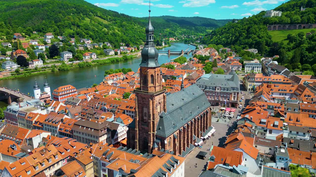 4K Aerial Drone Video of Historic Heiliggeistkirche Church on Neckar River with Castle on Königstuhl Hill overlooking Heidelberg, Germany