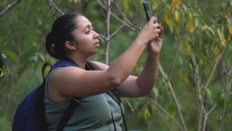 explorer woman with her backpack and camera sitting on a stone in the forest