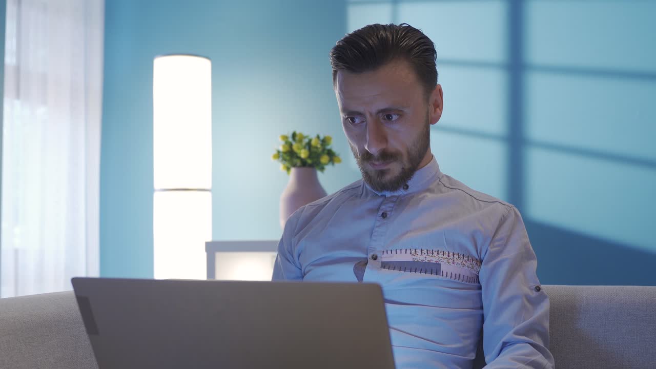 hombre elegante y elegante trabajando de forma remota en su casa por la noche usando una computadora portátil.