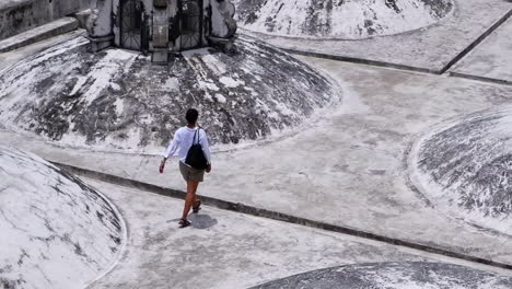 Woman-walks-amid-cupola-domes-atop-white-Basilica-Cathedral,-Nicaragua