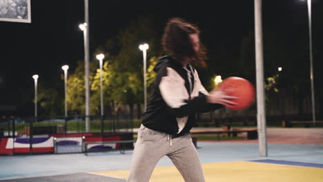 Konzentriertes-Weibliches-Basketballspielertraining-Mit-Ball-Auf-Dem-Außenplatz-Bei-Nacht-1